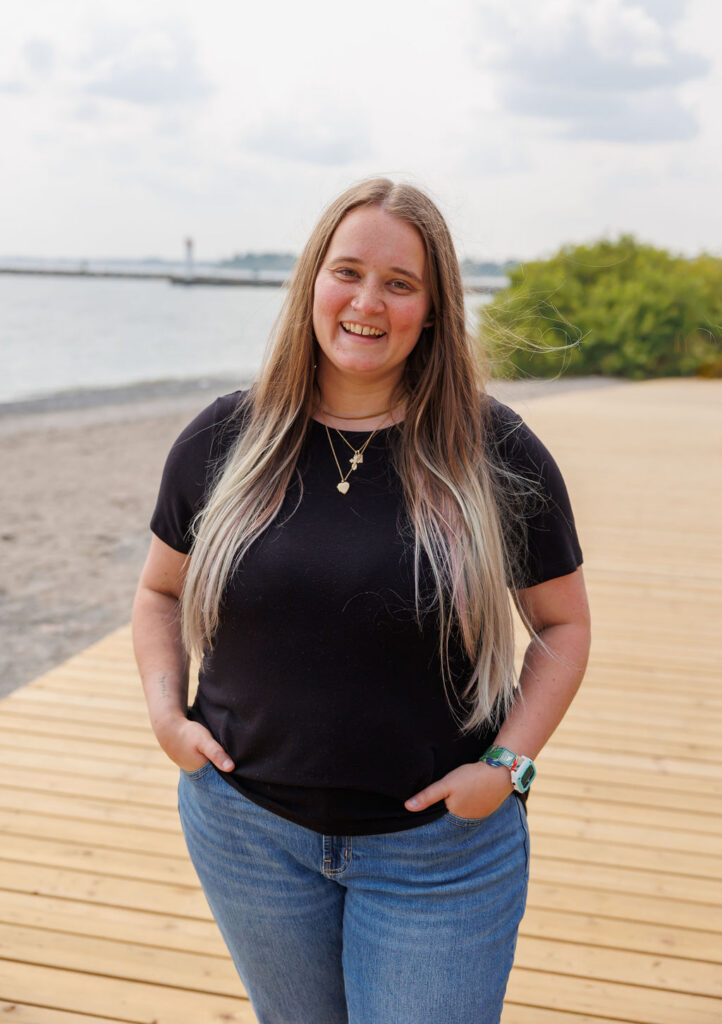 Dana, a bookkeeper, standing on a beach smiling at the camera