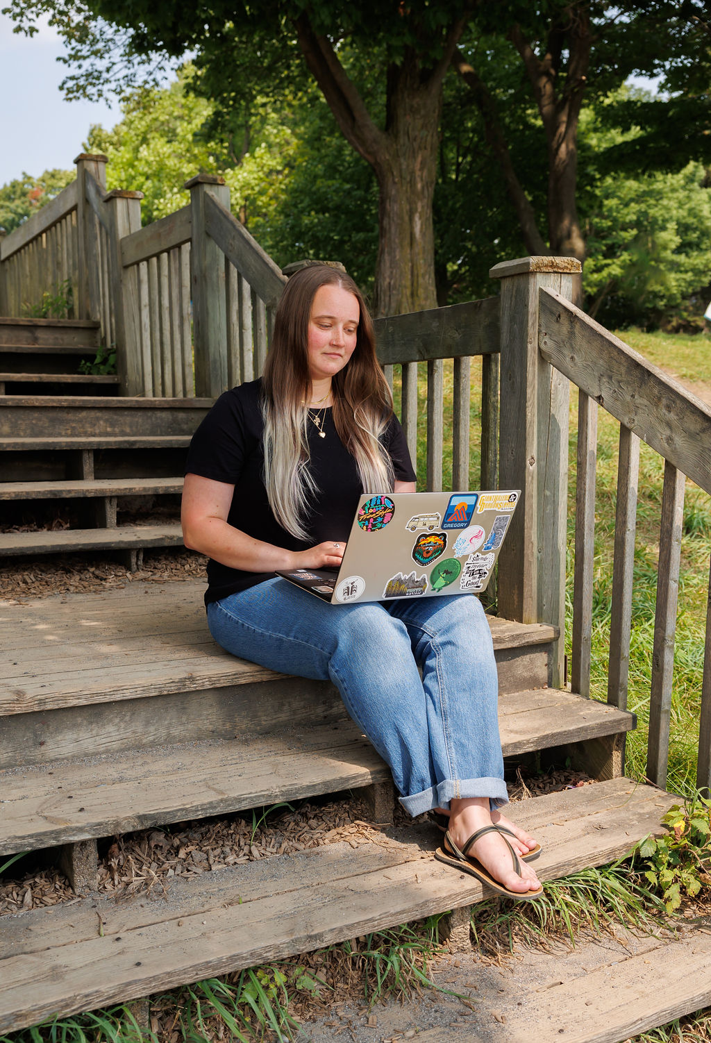 Dana, a bookkeeper, sitting on a step writing a blog post about HST for small business.