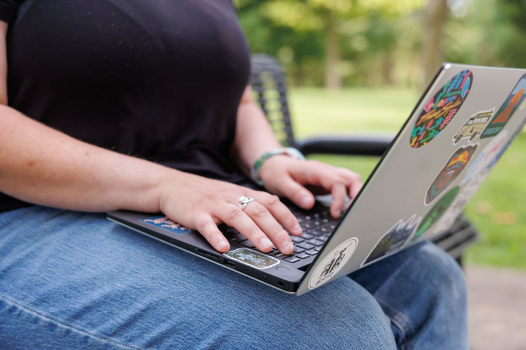 Dana sitting outside typing on a laptop, writing a blog post about why Wealthsimple is the best bank for Canadian small business owners.